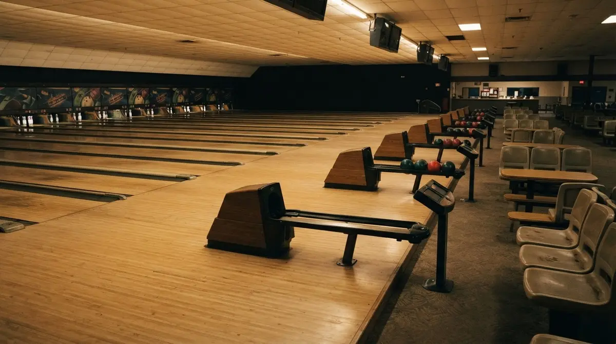 An empty bowling alley with rows of lanes, ball returns, and pins set up, no one there